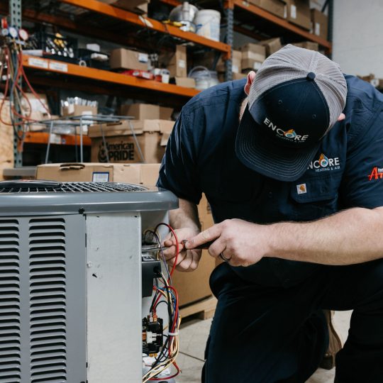 HVAC technician repairing air conditioner in Carver, MN home.
