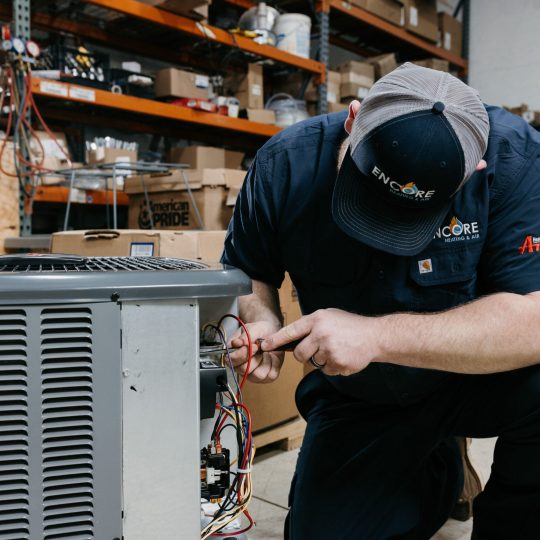 HVAC technician repairing air conditioner in Carver, MN home.